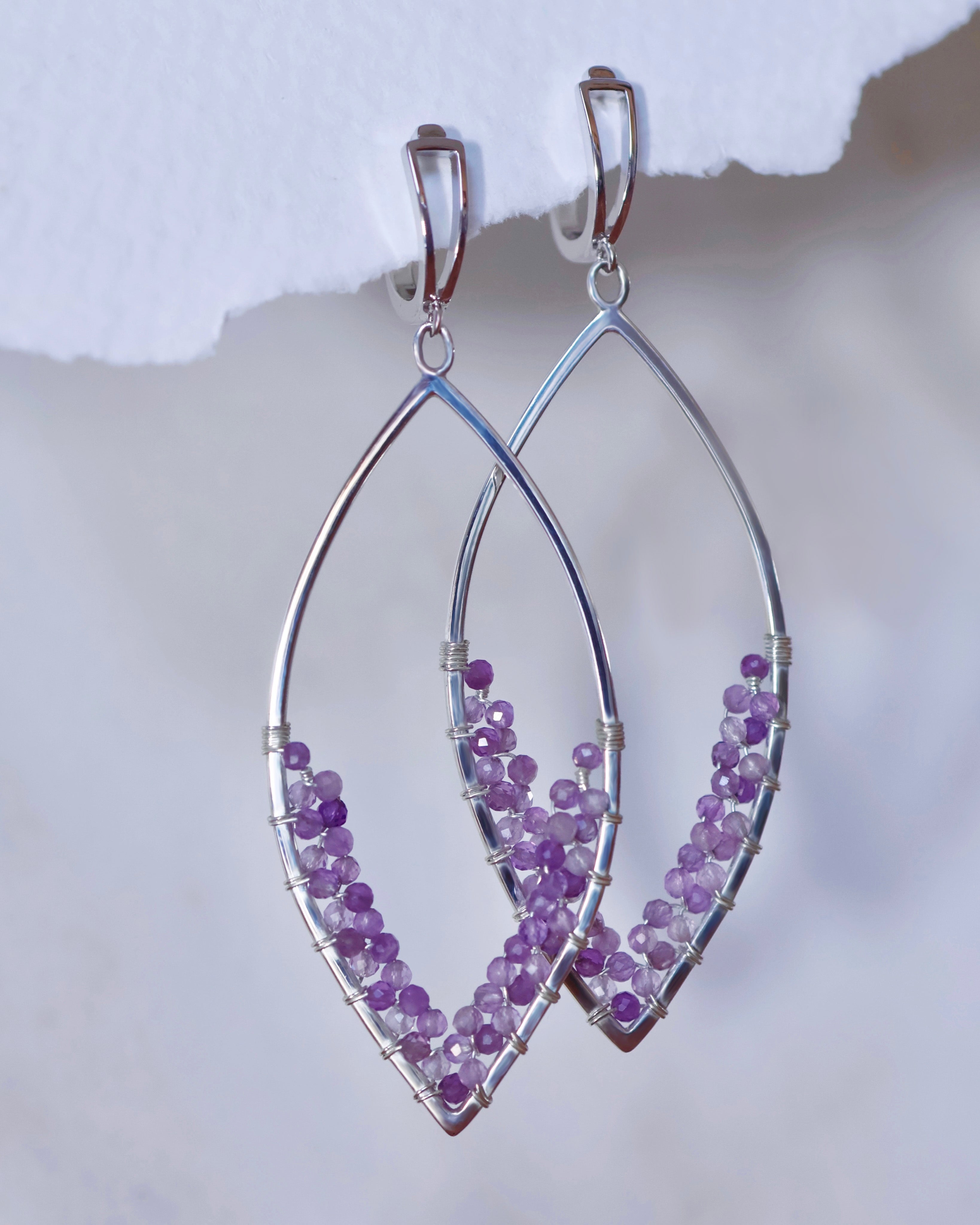 Amethyst Earrings by Lilac Sky Studio feature sterling silver marquise shapes with handwoven amethyst beads along the lower half, displayed on a light background.