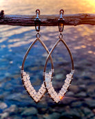 Aquamarine Earrings by Lilac Sky Studio: Sterling silver wire earrings with small clear beads and lever-back ear wires, shown hanging from a branch with sunlight on water in the background.