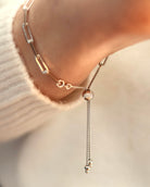 A close-up of the Lilac Sky Studio Treasure Mountain Turquoise Bracelet No. 1, featuring a turquoise bead and adjustable cable chain worn on a wrist, with part of a white sweater visible.