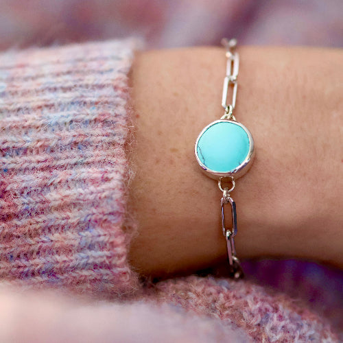 Slide-closure bracelet featuring a turquoise stone on a wrist with a blurred background