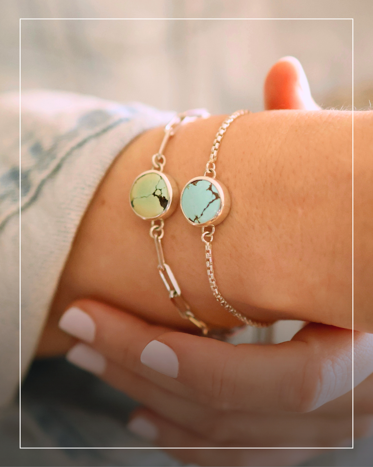 A close-up of a wrist wearing two silver bracelets with round, ethically sourced turquoise gemstones, set against a blurred neutral background.