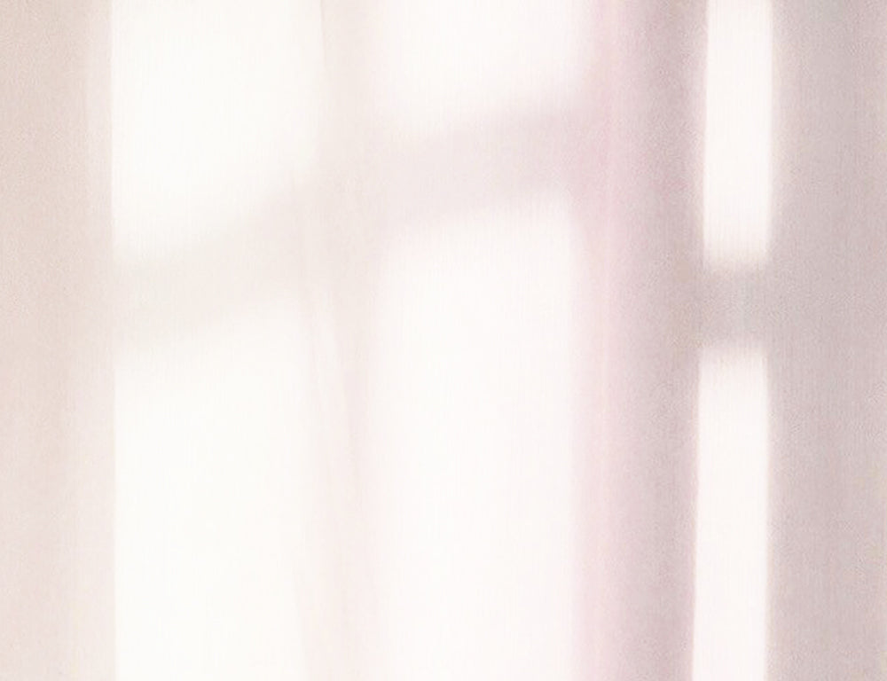 Soft sunlight filters through a sheer white curtain, casting gentle shadows that highlight ethically sourced gold jewelry, creating a calm, serene atmosphere.