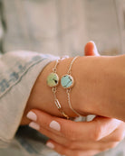 A close-up of a person wearing the Lilac Sky Studio Treasure Mountain Turquoise Bracelet No.3, showing round turquoise stones in sterling silver as they hold their wrist with the opposite hand.