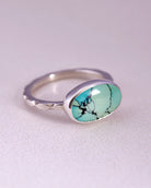Sterling Silver ring with a turquoise stone and a starburst pattern band on a light gray background