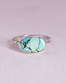 Sterling Silver ring with a turquoise stone and a starburst pattern band on a light gray background