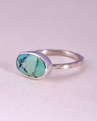 Sterling Silver ring with a turquoise stone and a starburst pattern band on a light gray background